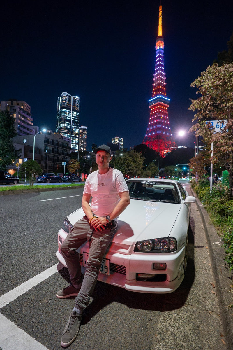 Akebono client sitting on a white Skyline R34 in front of Tokyo Tower at night