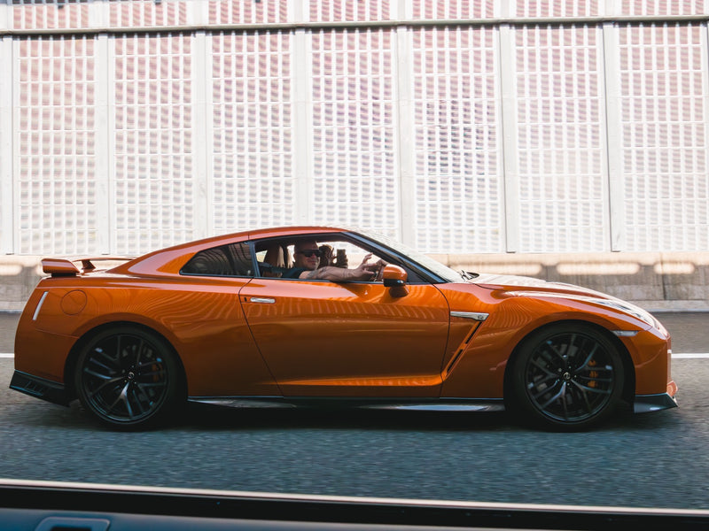 Client waving from an orange GT-R on the Tokyo expressway