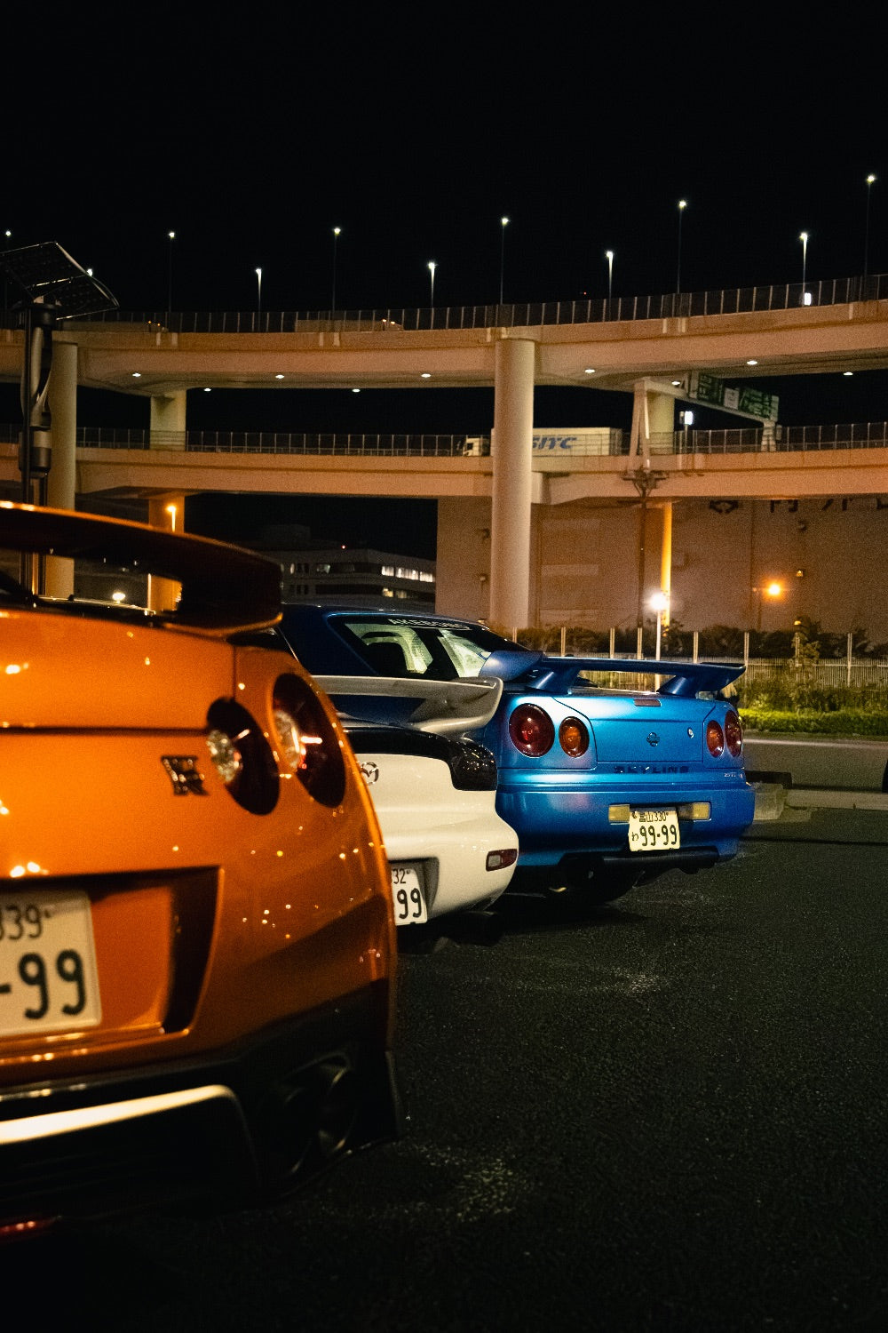 Nissan GT-R, Mazda RX-7 and Skyline R34 lined up at Daikoku PA at night